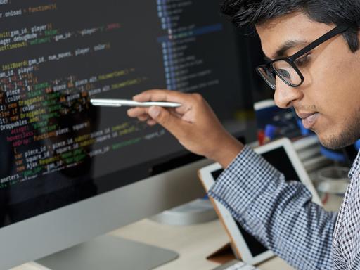 male data scientist looking at data sheet confirming coding