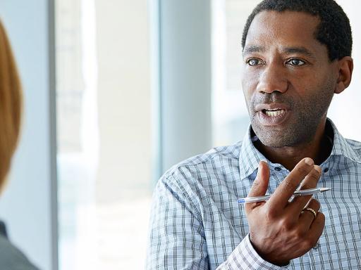 Man facing camera, back of woman's head in a discussion