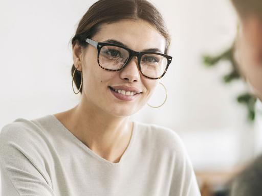 woman with glasses across the table from two other people