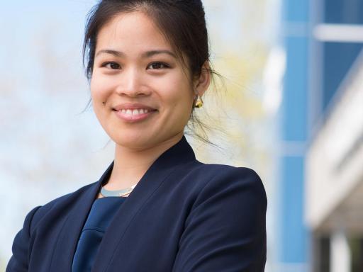 Adult female student in front of office building smiling at camer