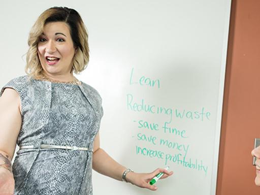 Blond woman at white board speaking to two other women, 