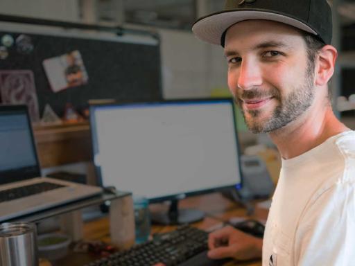 Male student at work station smiling