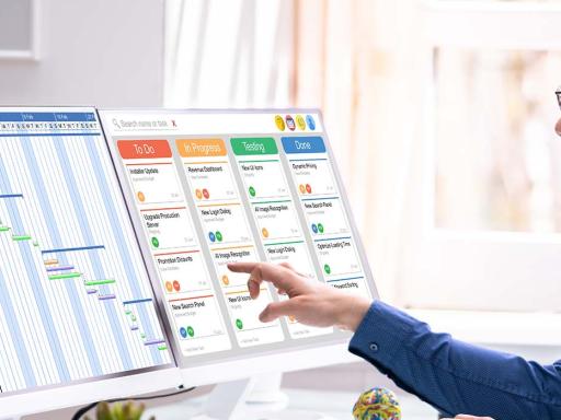 Man looking at gantt chart and other chart on two computer monitors