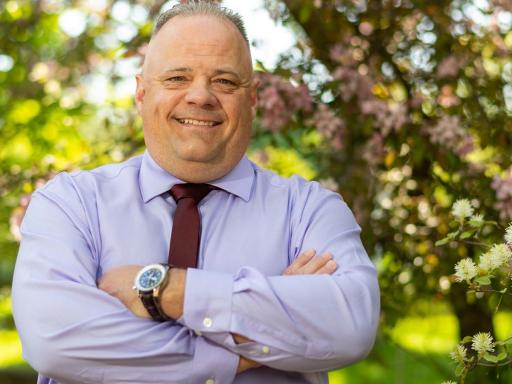 older white male dressed in button down shirt and maroon tie