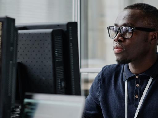 man at desktop computer with code on screen