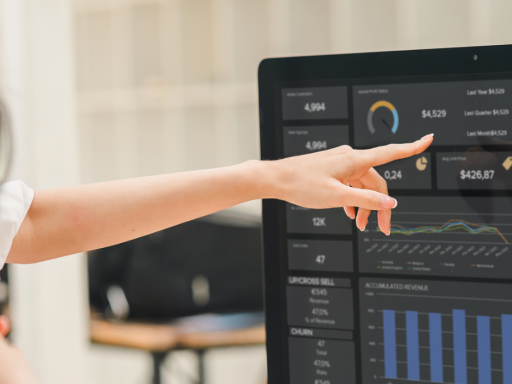 women at desktop monitors pointing at data on the screen