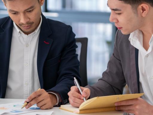 Two men at a desk working on paper