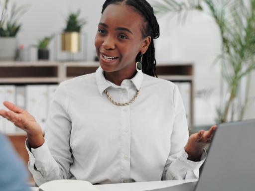 womans talking to man sitting around an open laptop