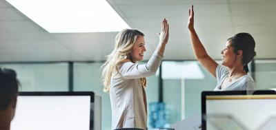 Two professionals giving each other high five in the workplace