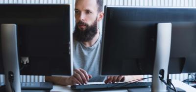 Adult male student work on dual monitors concentrating