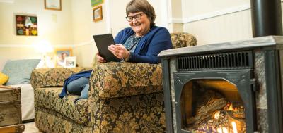 Female student working on tablet next to her fireplace while sitting on her couch