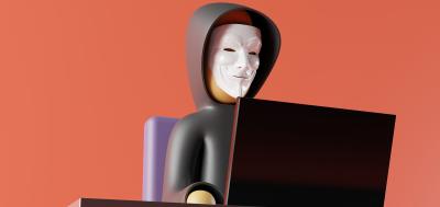 Figure of anonymous man in mask sitting in front of computer