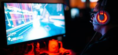 Man in dark room playing video game on computer