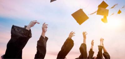 College commencement graduates throw caps in air