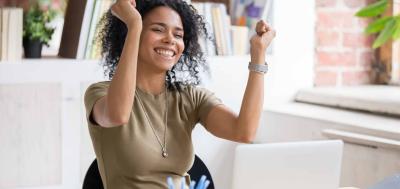 Happy woman celebrating while sitting behind a laptop