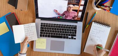 Birds eye view of student working on Macbook laptop taking notes on a notepad