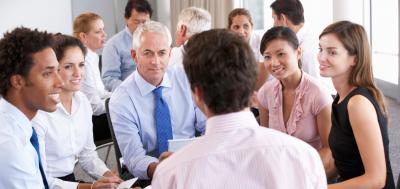 Smiling Businesspeople Seated In Circle At Company Seminar.