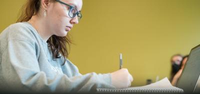 Female student sitting at a desk while taking notes.