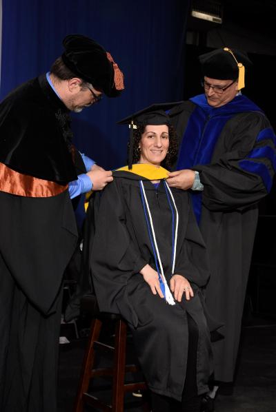 Female student sitting, receiving a graduation stole