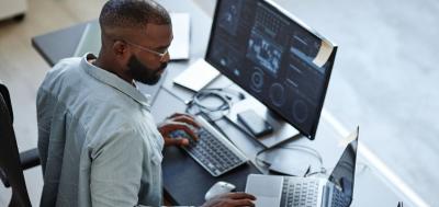 Minimal high angle view at African American software developer working with computers and data systems in office