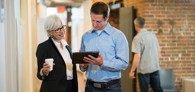 Managers discussing something on an iPad in a hallway