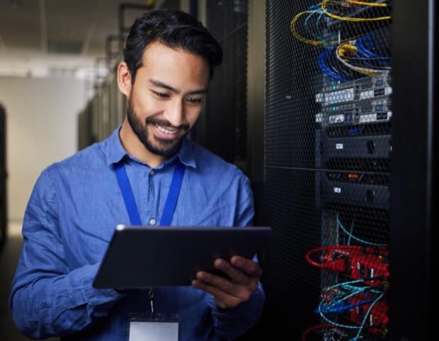 Information security professional looking at iPad next to server.