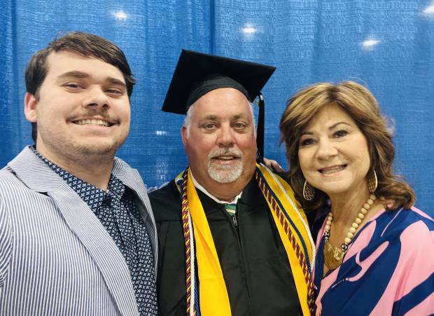 Male graduate with son and wife by his side.