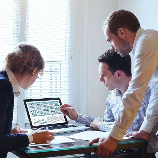 Group of three coworkers looking at a spreadsheet on a computer