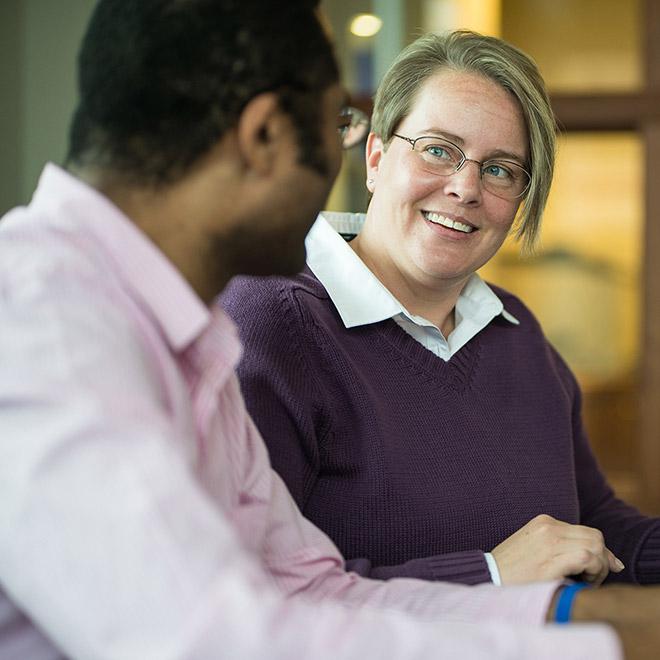 Online positive organization certificate student talking a colleague in an office setting