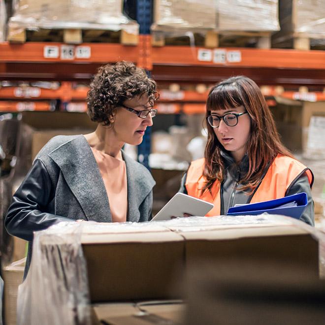 Online supply chain certificate leader with factory employee discussing work in warehouse with tablet