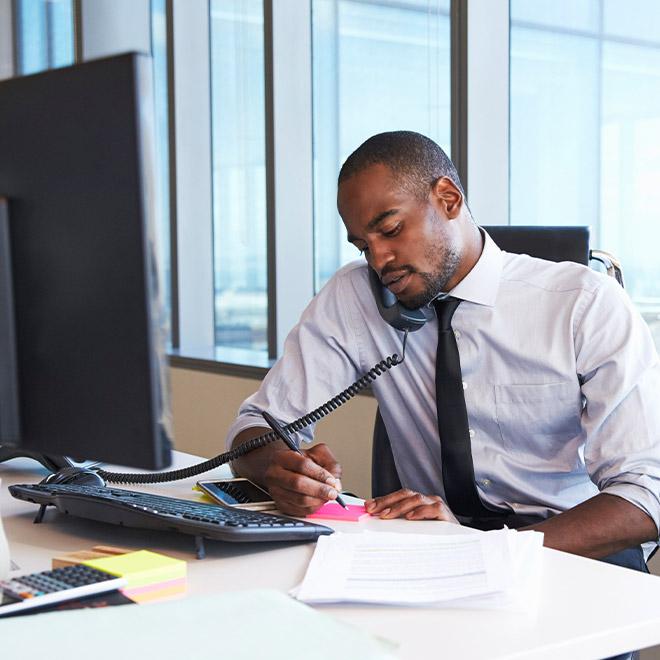 Man in an office on the phone looking over papers