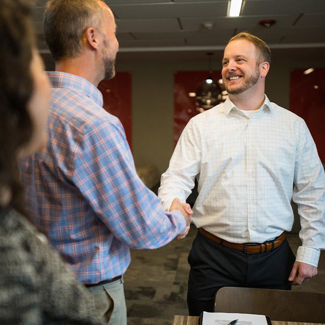 Business Management online degree recipient shaking hands and greeting colleagues 