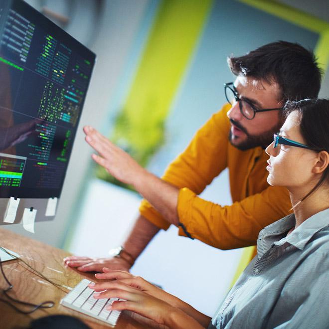 Man and woman looking at computer screen with code on it