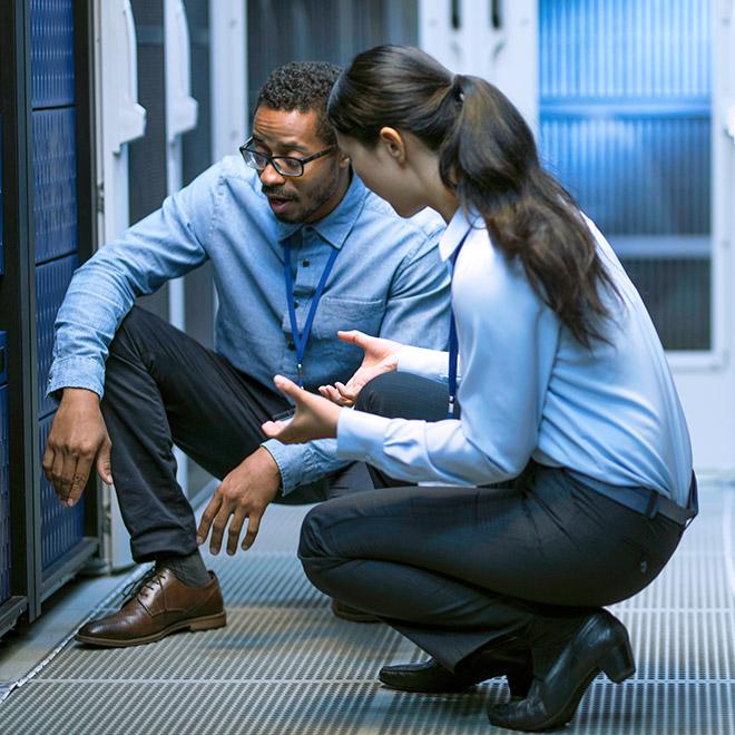 Online information security graduate certificate graduate working in large scale server room with colleague