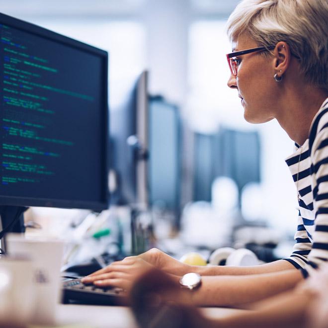 Woman looking at a computer screen filled with code