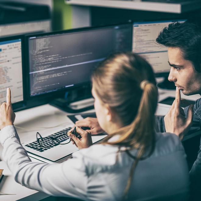 Man and woman looking at code on a computer scree