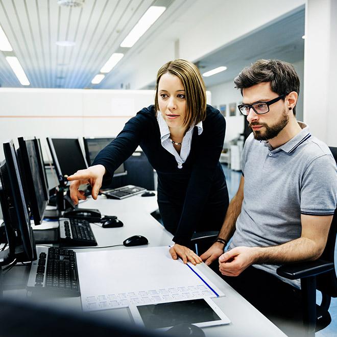 Computer and information systems online graduate collaborating with colleague in computer lab