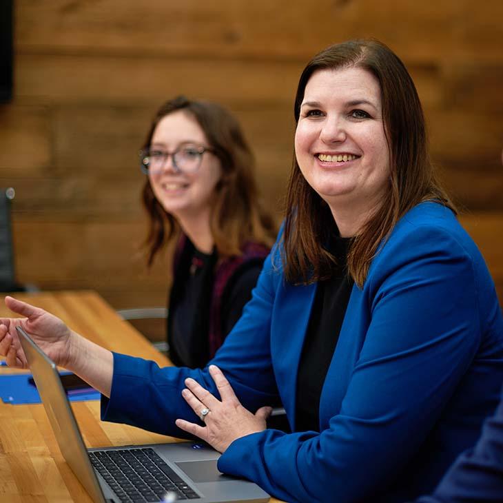 Two caucasian women, one being Jenn T, in a business meeting looking at the camera