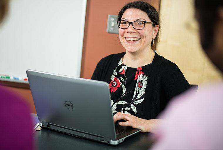 Champlain College Online advisor smiling with computer 