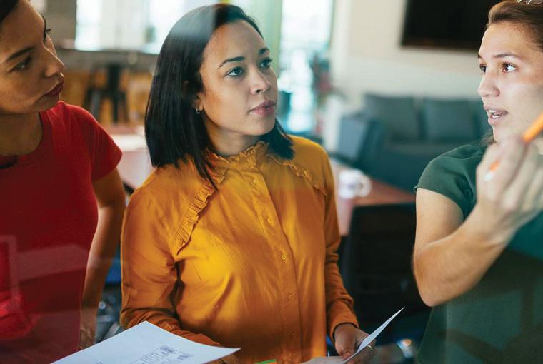 Three female colleagues brainstorming in office setting