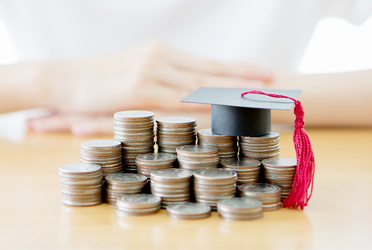 Stacks of quarters lined up, increasing as they go with miniture graduation cap at the top 