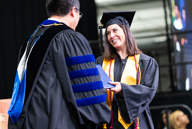 Champlain Presidet Alex Hernandez shaking hand of CCO female graduate on stage